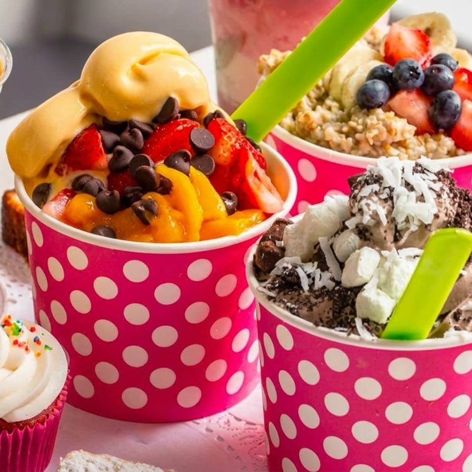 Assortment of colorful frozen yogurt cups with various toppings, smoothies, and desserts.