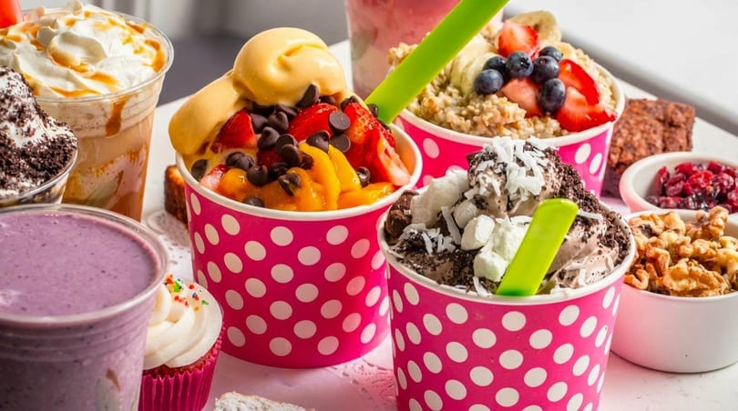 Assortment of colorful frozen yogurt cups with various toppings, smoothies, and desserts.
